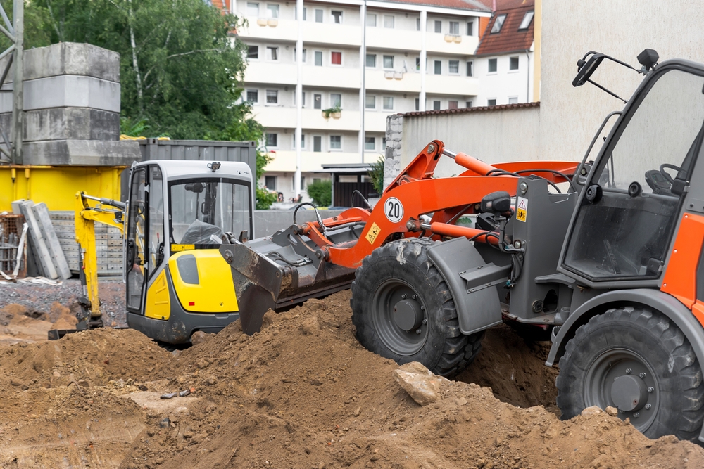 Small,loader,and,excavator,digger,machine,moving,heap,of,earth
